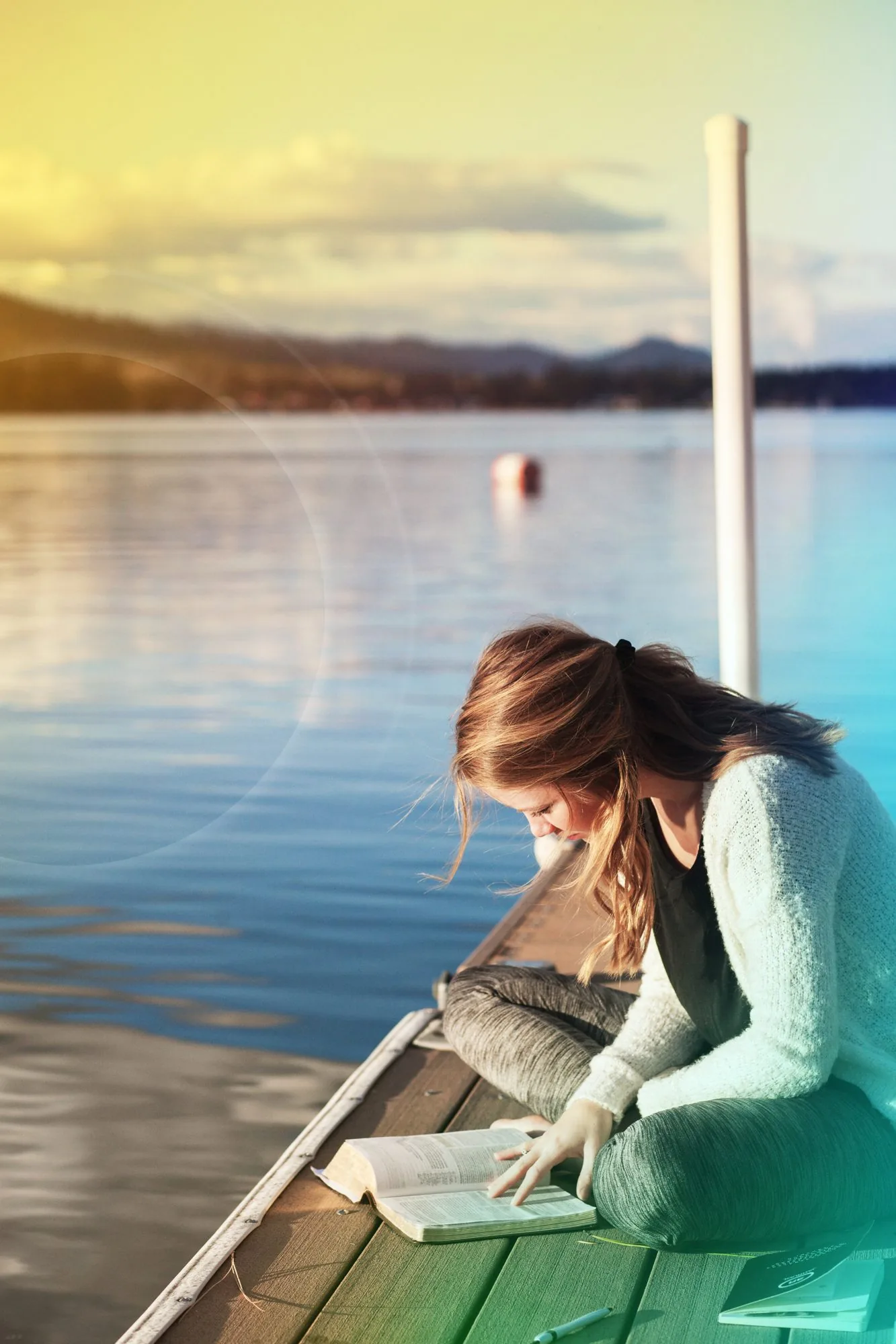 Woman reading by the water in evening light