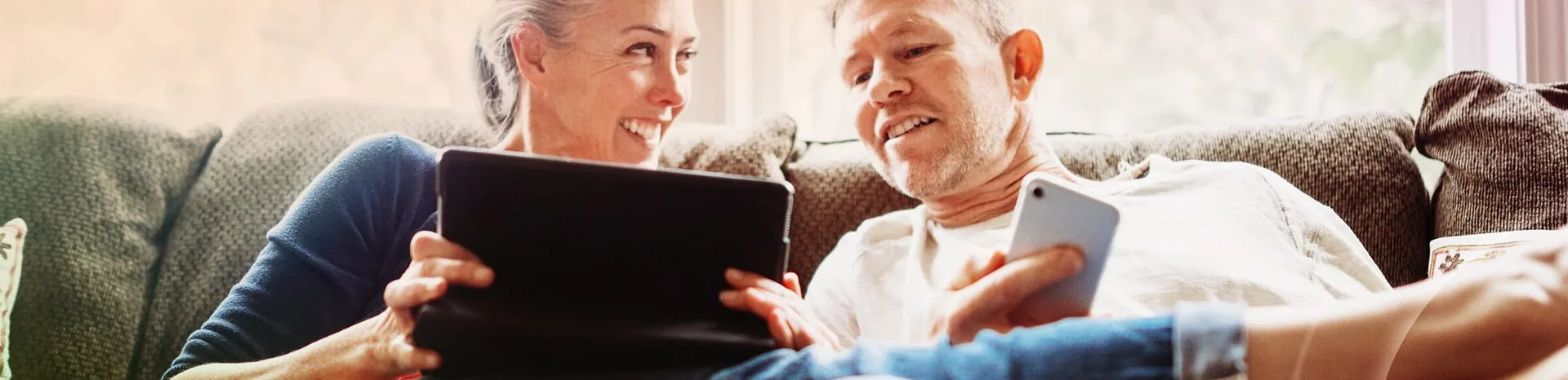 A couple reading together on the sofa at home