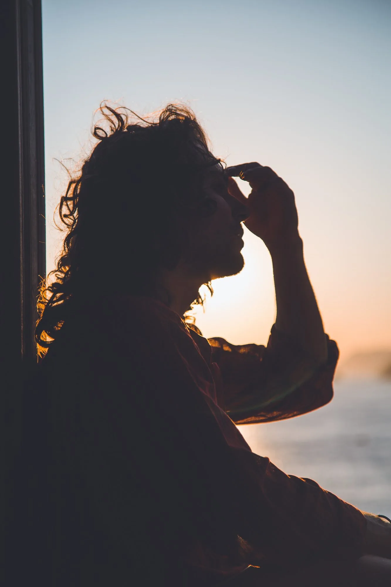 Silhouette of a woman shielding her eyes from low sun
